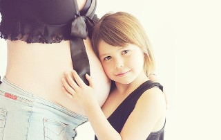 Child hugging a tummy of a pregnant woman
