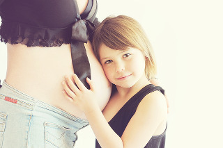 Child hugging a tummy of a pregnant woman